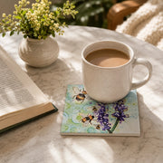 Bumblebee and Lavender ceramic coaster on marble table with coffee mug, open book and plant in morning light
