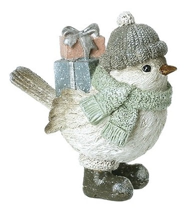 Christmas bird figurine with sparkly finish wearing a bobble hat and sage green scarf, carrying a stack of glittery gift boxes, standing in chunky boots