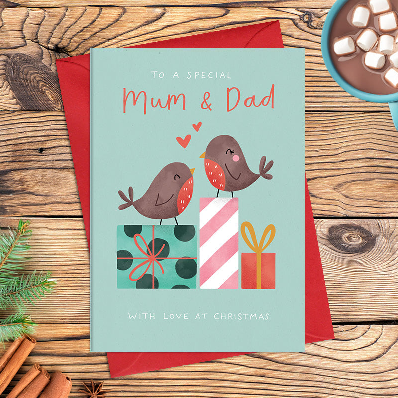 Special Mum and Dad Christmas card featuring two illustrated robins perched on patterned wrapped presents with hearts above them, with the message ‘With love at Christmas