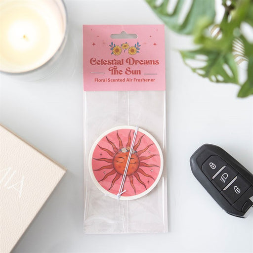 Celestial Dreams The Sun floral scented air freshener in packaging on a white surface beside a car key and candle