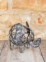 Open ironwork elephant ornament handmade in Bali, twisted and looped wire body with flat metal ears, gold-coloured detail markings and bead eyes, curled wire trunk and tail, 11cm tall