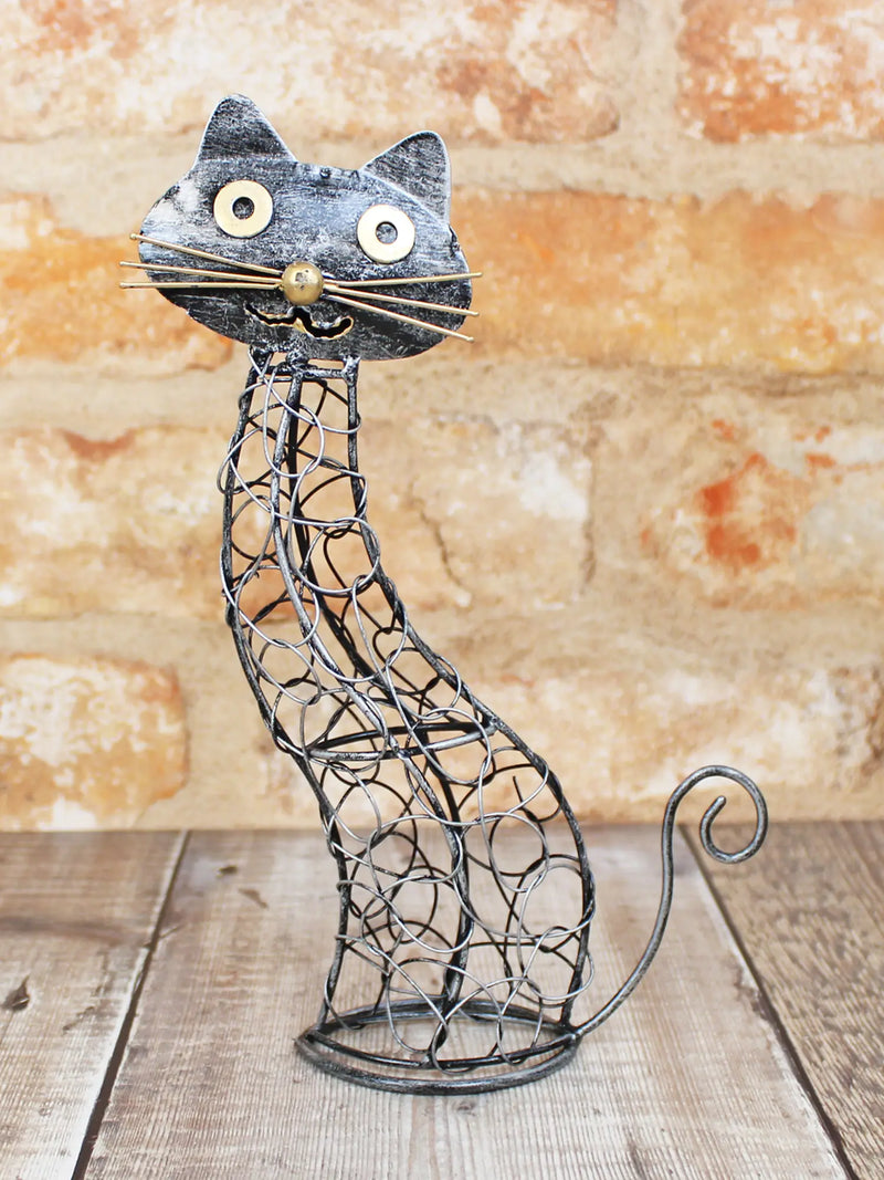 Open ironwork cat ornament handmade in Bali, twisted and looped wire body with flat metal head, gold-coloured eyes, nose and whiskers, curled wire tail, 22cm tall