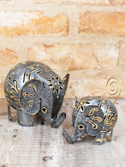 Small and large dark metal elephant ornaments handmade in Bali, dark metal finish with intricate gold-coloured cut-out patterns, small has curly gold-coloured wire tail