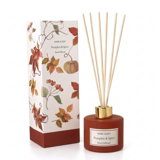 Pumpkin and Spice Reed Diffuser in a terracotta-red frosted glass bottle with a gold collar and natural reed sticks, shown alongside its autumn botanical gift box decorated with red maple leaves, pumpkins, and berries, on a white background