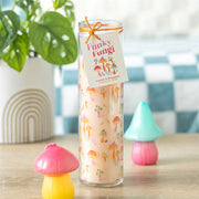 Funky Fungi Lemon & Bergamot tube candle in glass jar with orange twine bow and gift tag, styled on a wooden surface with colourful mushroom ornaments and a plant in the background