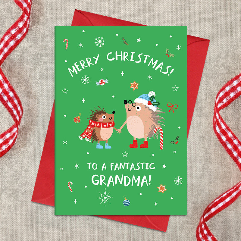 Fantastic Grandma Christmas card featuring two illustrated hedgehogs holding hands in festive accessories, surrounded by snowflakes and decorations, with a Merry Christmas greeting.