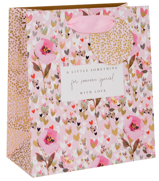 Stephanie Dyment Hearts and Flowers medium gift bag with pink floral and hearts design, gold foil dot accents, sentiment label and pink ribbon handles on white background