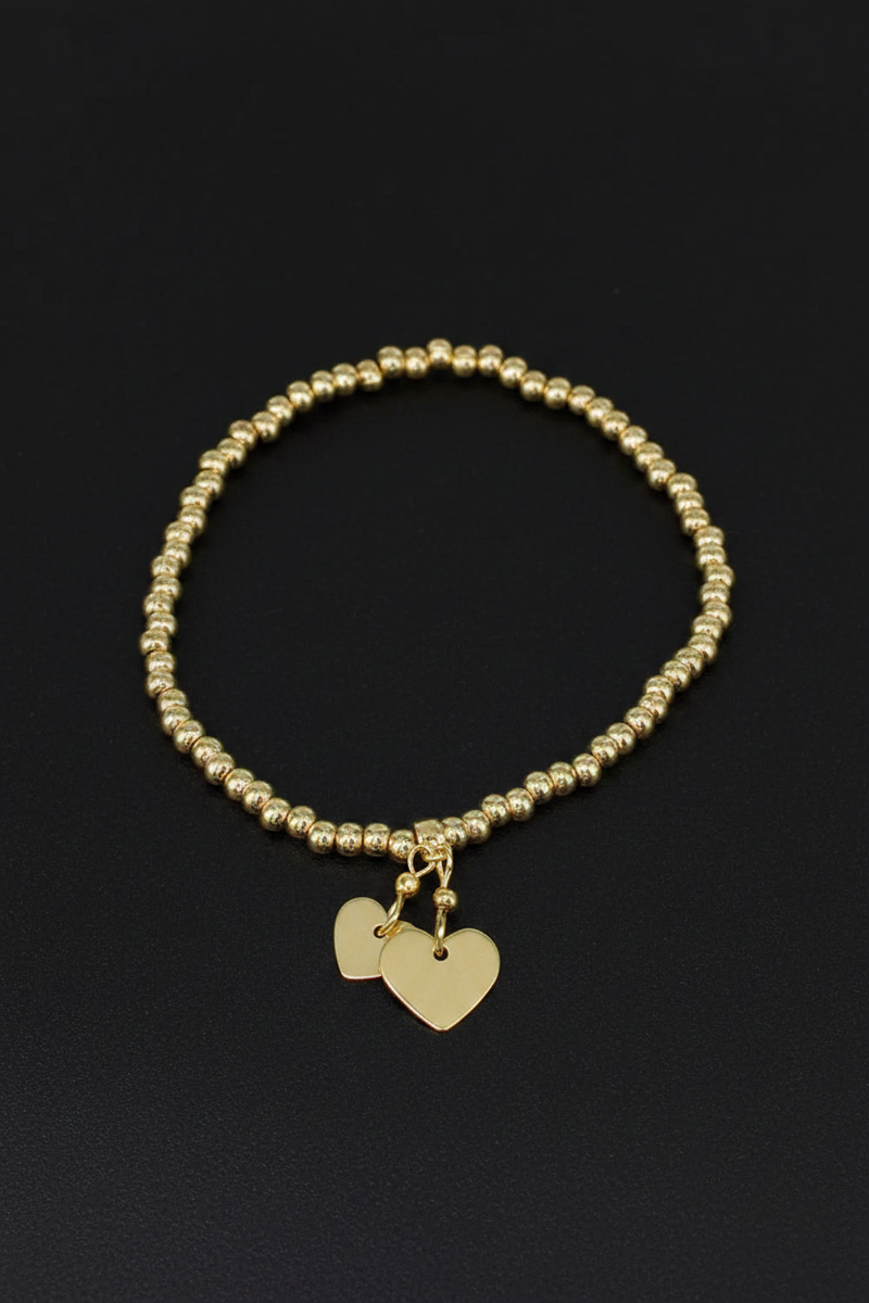 18ct gold plated elasticated round bead bracelet with two dangling flat heart charms on a black background