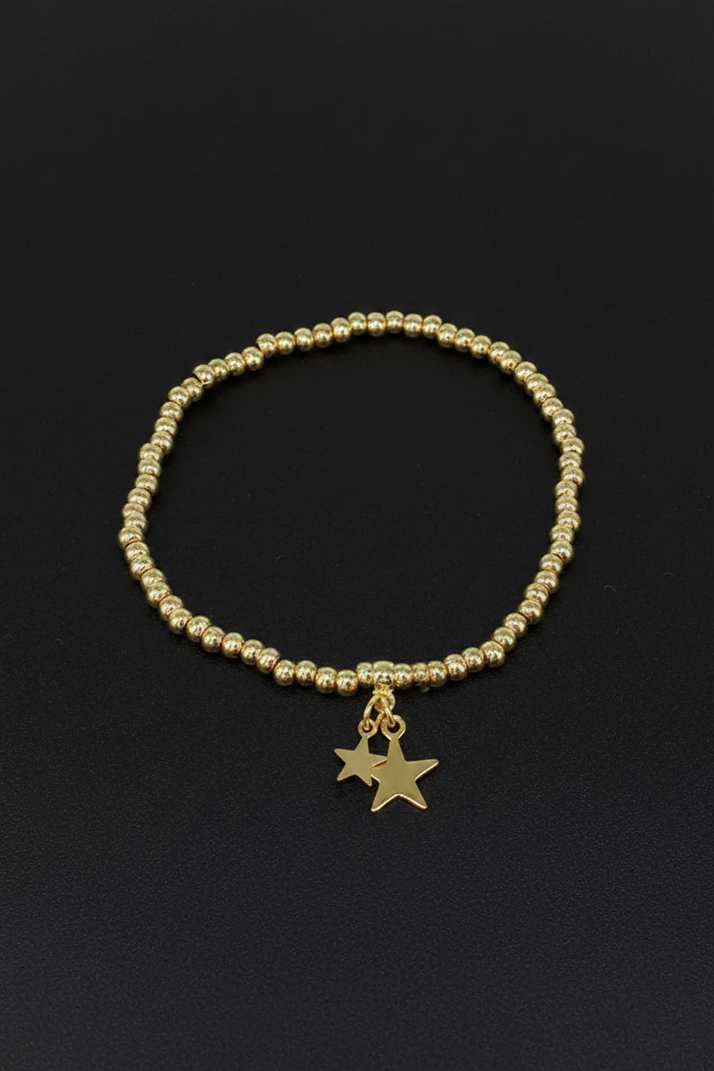 18ct gold plated elasticated round bead bracelet with two dangling star charms on a black background