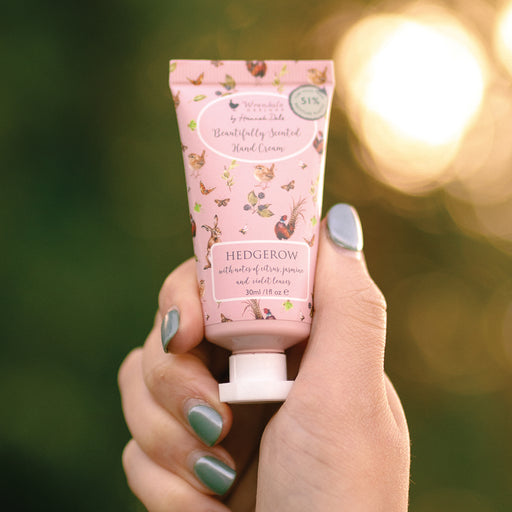 Wrendale Designs Hedgerow hand cream held in a hand against a sunlit garden background