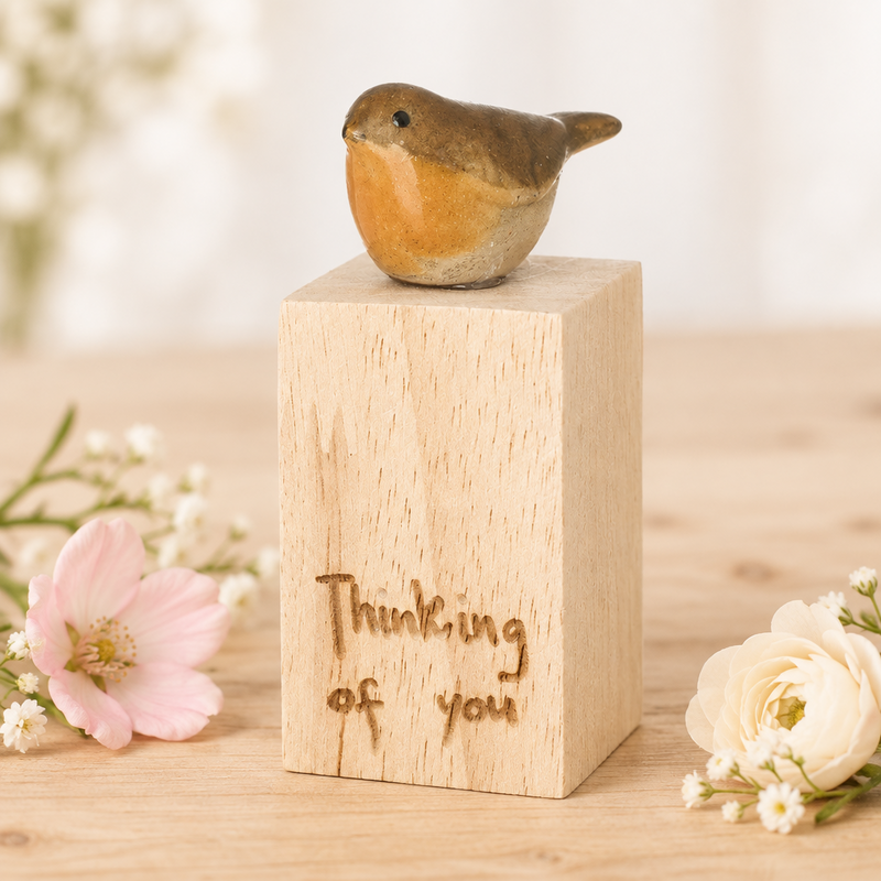 Thinking of You robin wood block on a light wooden surface with delicate flowers alongside and a soft neutral background