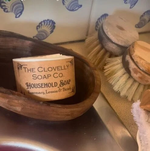 Clovelly Soap Co. Household Soap bar with lemon, rosemary and bicarb, sitting in a wooden bowl beside natural scrubbing brushes, handmade in Devon
