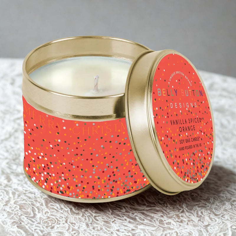 Belly Button Designs Vanilla Spiced Orange soy wax candle in red and gold confetti tin on white lace fabric, grey background