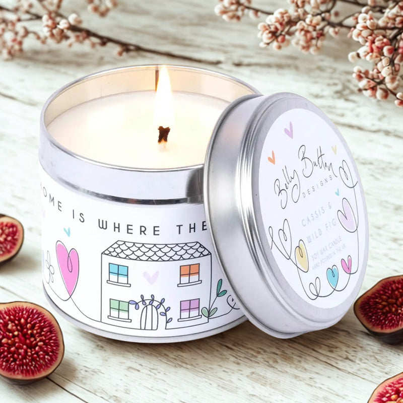 Home Is Where The Heart Is Fig & Cassis soy lit candle 195g, with lid leaning against the candle, styled on a wooden surface with figs and frosted berries