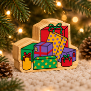 Wooden Christmas stack of presents toy on a soft rug beneath a Christmas tree, with small pinecones and warm fairy lights