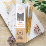 Champa and Olibanum Thick Incense Sticks, lifestyle shot of packaging and three incense sticks on marble board with dried flowers, wooden surface background