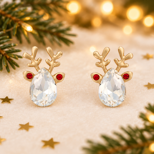 Pair of gold plated crystal reindeer earrings laid on a soft warm cream surface, surrounded by gold star confetti and evergreen sprigs with warm golden fairy lights in the background