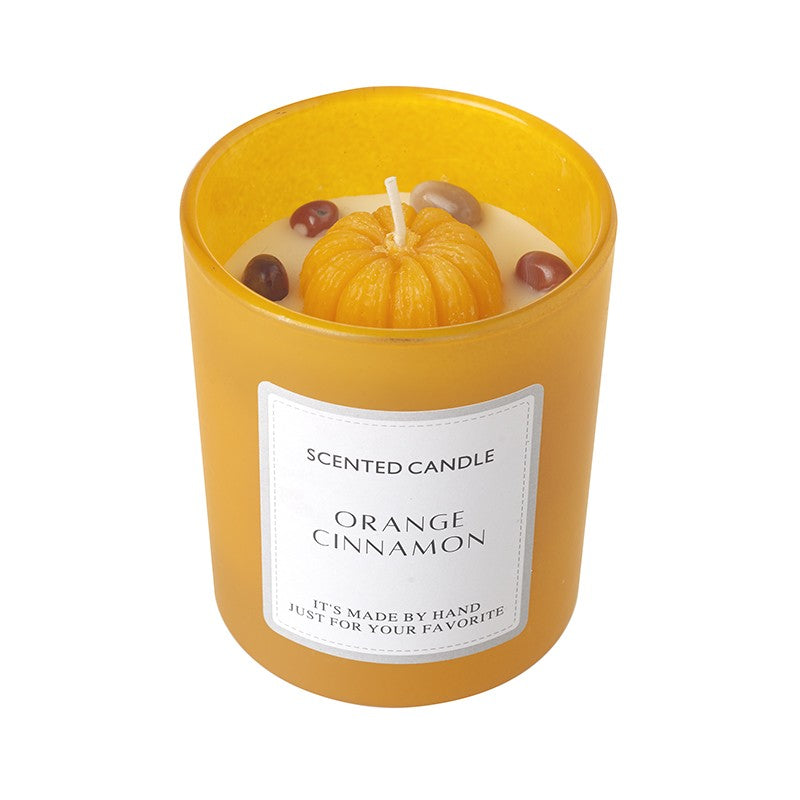 Orange Cinnamon Scented Candle in an amber yellow frosted glass jar with a wax pumpkin top with wick and small decorative accents, with Orange Cinnamon Scented Candle label, on a white background