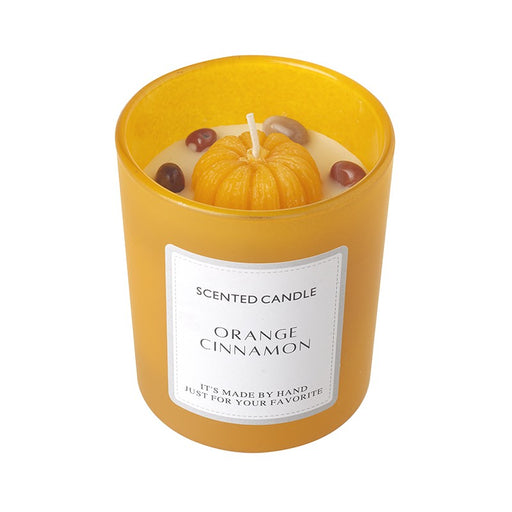 Orange Cinnamon Scented Candle in an amber yellow frosted glass jar with a wax pumpkin top with wick and small decorative accents, with Orange Cinnamon Scented Candle label, on a white background