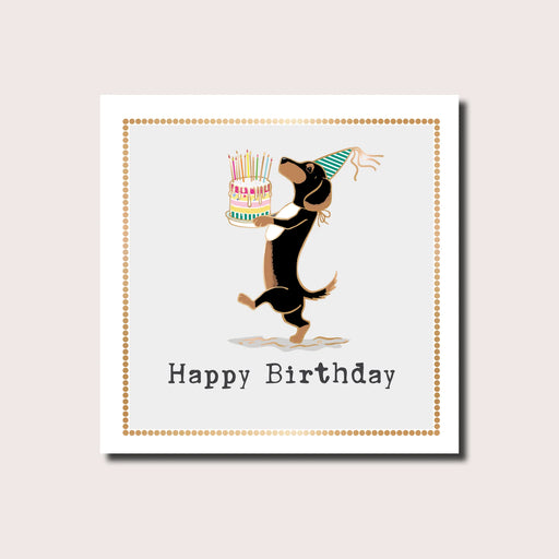 Happy birthday card featuring a dachshund in a party hat presenting a candle-topped birthday cake, gold dot border, gold foil finish, blank inside, square format 155 x 155mm