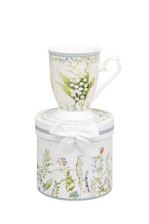 Snowdrop Mug in Gift Box footed mug with snowdrop print sitting on top of a matching cylindrical gift box with wildflower meadow design and white ribbon bow on white background