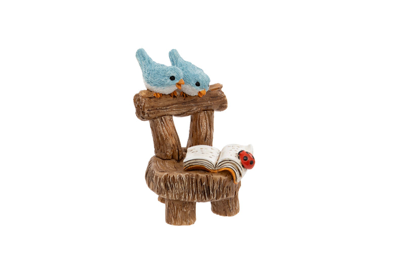 Blue Birds on Chair Ornament polyresin figurine of two blue birds perched on the back of a rustic log chair with an open book and ladybird on the seat on white background
