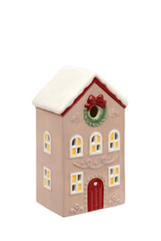 Juniper LED Cottage ceramic two-storey LED house in dusky pink with snow-capped red-trimmed roof wreath with red bow glowing windows and red front door with heart detail on white background