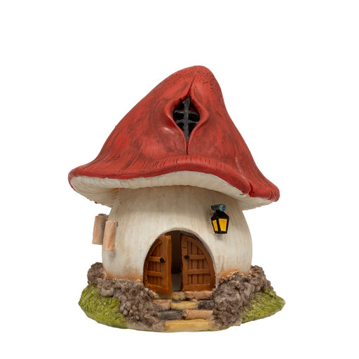 Mushroom House LED Ornament, red toadstool roof with diamond-pane attic window, cream stem body with arched wooden double door, glowing wall lantern, stone path with steps and mossy grassy base, on white background