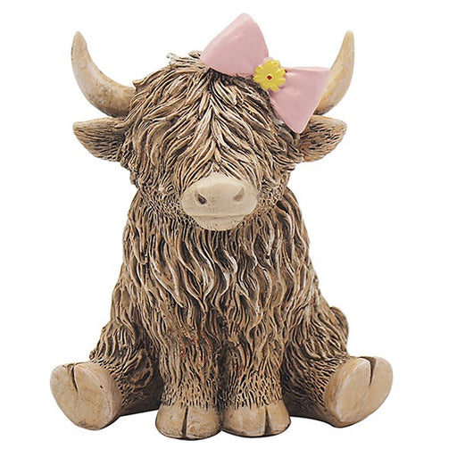 Highland Cow figurine with pink bow and yellow flower, shaggy brown coat, seated position, on white background
