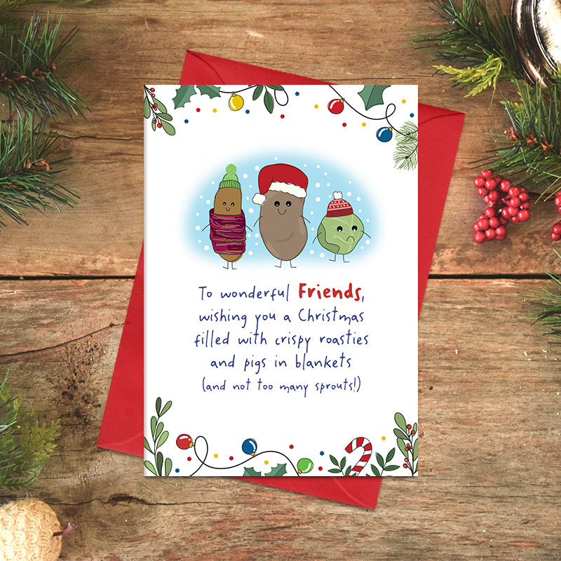 Wonderful Friends Christmas card featuring illustrated pigs in blankets, roast potato and sprout characters wearing festive hats, with a Christmas dinner joke and festive foliage border