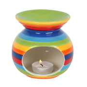 Rainbow Stripe Oil Burner, front view showing round ceramic body with bold rainbow stripes and oval tealight cut-out with lit tealight, white background