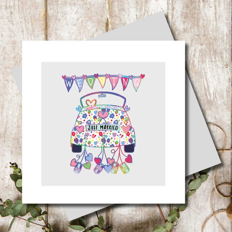 Just married wedding card featuring a patterned car covered in hearts and flowers with tin cans trailing behind and colourful wedding bunting above, blank inside, square format 155 x 155mm