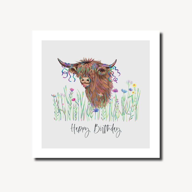 Happy birthday card featuring a shaggy highland cow with colourful party streamers in its fringe peeking through a wildflower meadow on a soft grey background, blank inside, square format 155 x 155mm