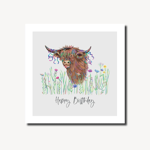 Happy birthday card featuring a shaggy highland cow with colourful party streamers in its fringe peeking through a wildflower meadow on a soft grey background, blank inside, square format 155 x 155mm