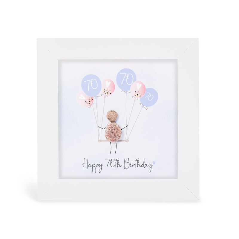 "Happy 70th Birthday" mini plaque, white frame with a pebble figure sitting on a swing holding a bunch of pink and lilac balloons printed with the number 70