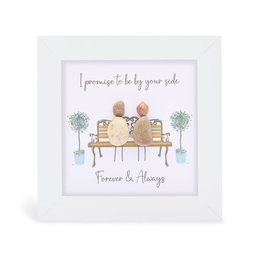 Pebble art framed plaque with two natural pebble figures sitting on an ornate bench flanked by illustrated topiary trees, with the sentiments "I promise to be by your side" and "Forever & Always", white frame