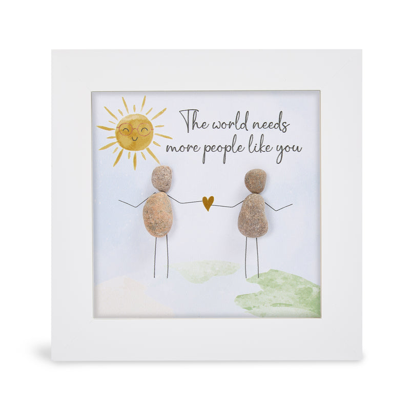 Pebble art framed plaque with two natural pebble figures holding a gold heart beneath a smiling sun and the sentiment "The world needs more people like you", white frame