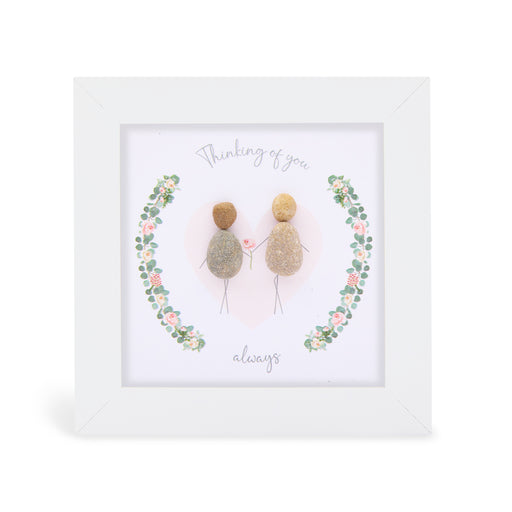 Pebble art framed plaque with two natural pebble figures holding a flower inside an illustrated floral wreath and the sentiment "Thinking of you always", white frame