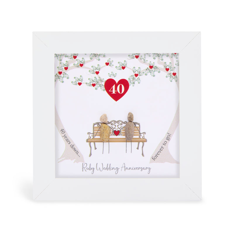 Pebble art framed plaque with two natural pebble figures on an ornate bench beneath a tree with ruby red hearts, a red heart with the number 40 above them, and the sentiment "40 years down... forever to go! Ruby Wedding Anniversary", white frame