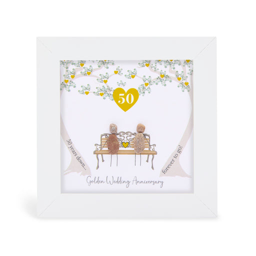 Pebble art framed plaque with two natural pebble figures on an ornate bench beneath a tree with gold hearts, a gold heart with the number 50 above them, and the sentiment "50 years down... forever to go! Golden Wedding Anniversary", white frame