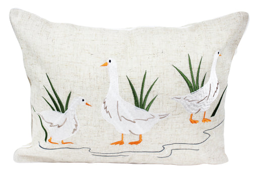 Puddles Embroidered Duck Cushion with three embroidered white ducks with orange beaks and feet in a puddle scene with green grass tufts on natural linen-mix background with white piped edge, 33 x 45 cm, on white background