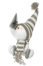 Sitting skating snowman decoration with grey striped bobble hat, knitted scarf, ice skates and miniature snow-dusted Christmas tree held aloft