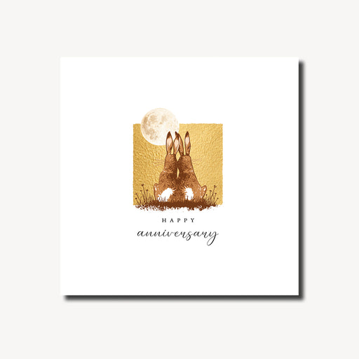 Happy anniversary card featuring two hares sitting side by side in a moonlit meadow with a full moon and warm gold foil background, blank inside, square format 155 x 155mm