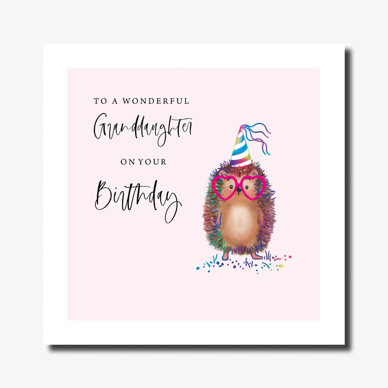 Birthday card for granddaughter with illustrated hedgehog in rainbow party hat and heart-shaped glasses on a soft pink background, with rainbow foil finish, 210 x 210mm