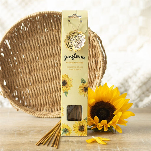 Sunflower Scented Incense Sticks with Holder, lifestyle shot of packaging standing upright with gold-tone sunflower holder attached, fresh sunflower and wicker tray in background