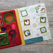 Spiro Wheels activity set open showing step-by-step instructions alongside red tray with wheels and pens