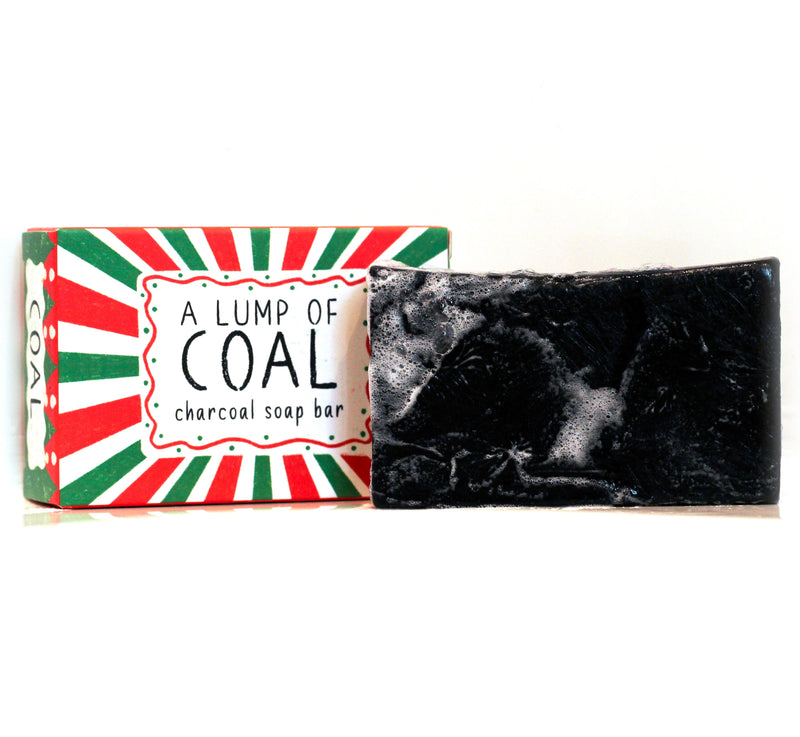 Neon Magpie Christmas Lump of Coal Vegan Soap Bar in red and green striped festive packaging with sunburst design, with dark charcoal soap bar shown alongside