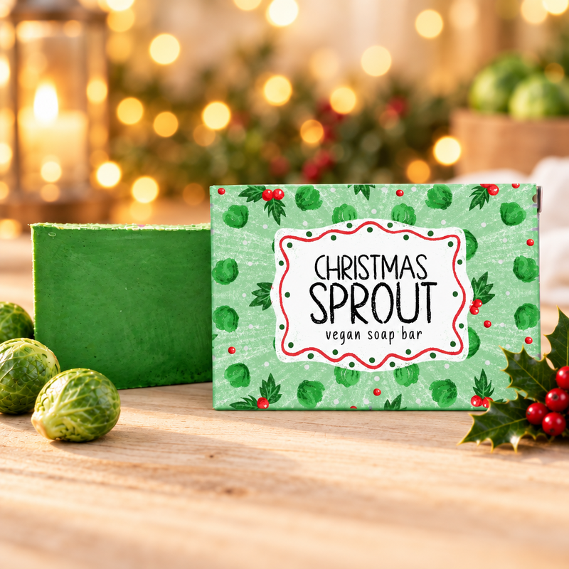 Neon Magpie Christmas Sprout Vegan Soap Bar in green packaging styled on a pale wooden surface with fresh brussels sprouts and holly, warm golden bokeh background