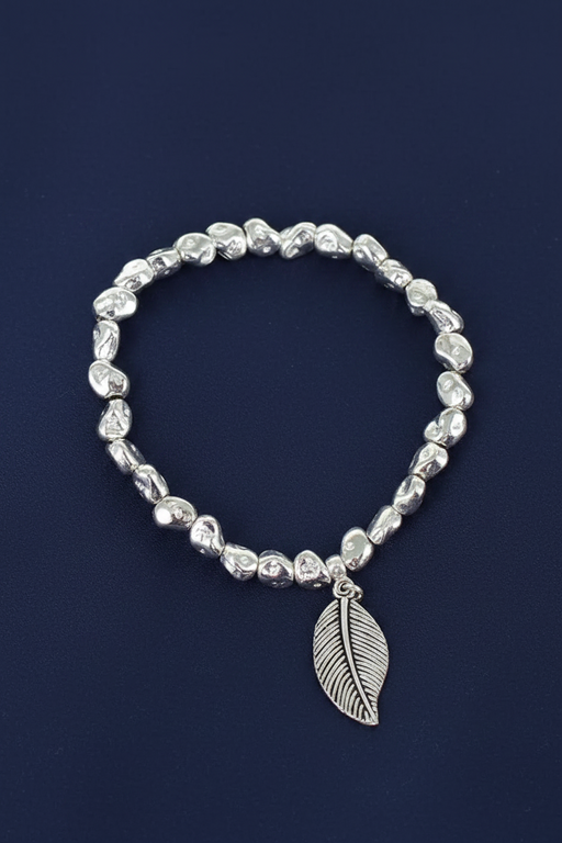 Silver plated nugget bead elasticated bracelet with a finely textured leaf charm on a deep navy blue background