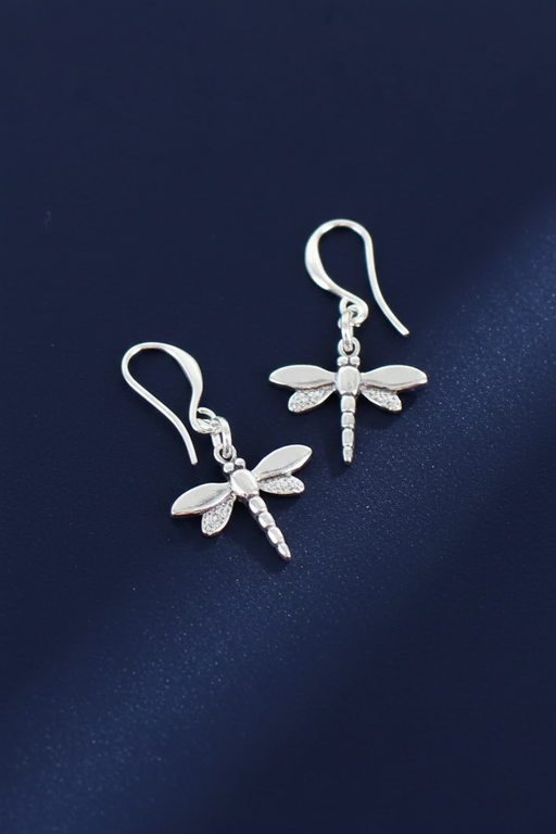 Silver plated dragonfly charm earrings with spread wings and segmented body on hook fittings, on a deep navy blue background